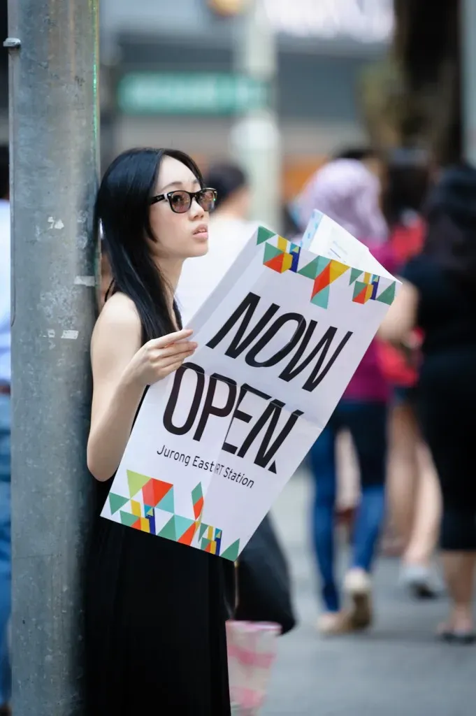 Girl holding newspaper that says "Now Open"