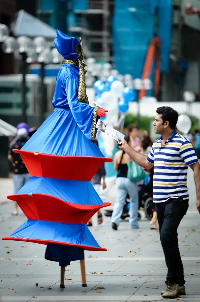 Man taking a flyer from a person on stilts