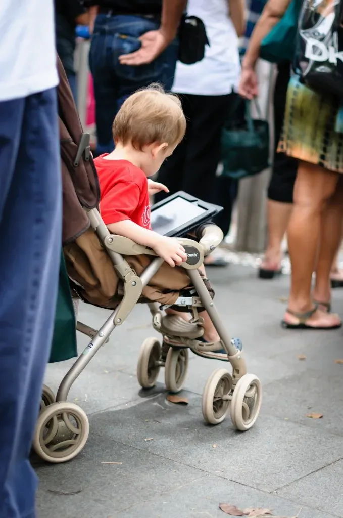 child in pram playing with iPad