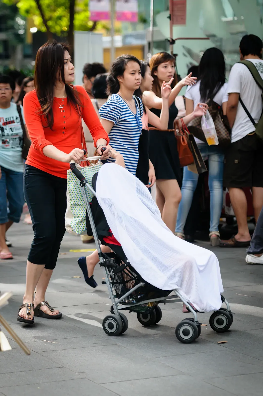 Mother pushing a pram draped with a white cloth