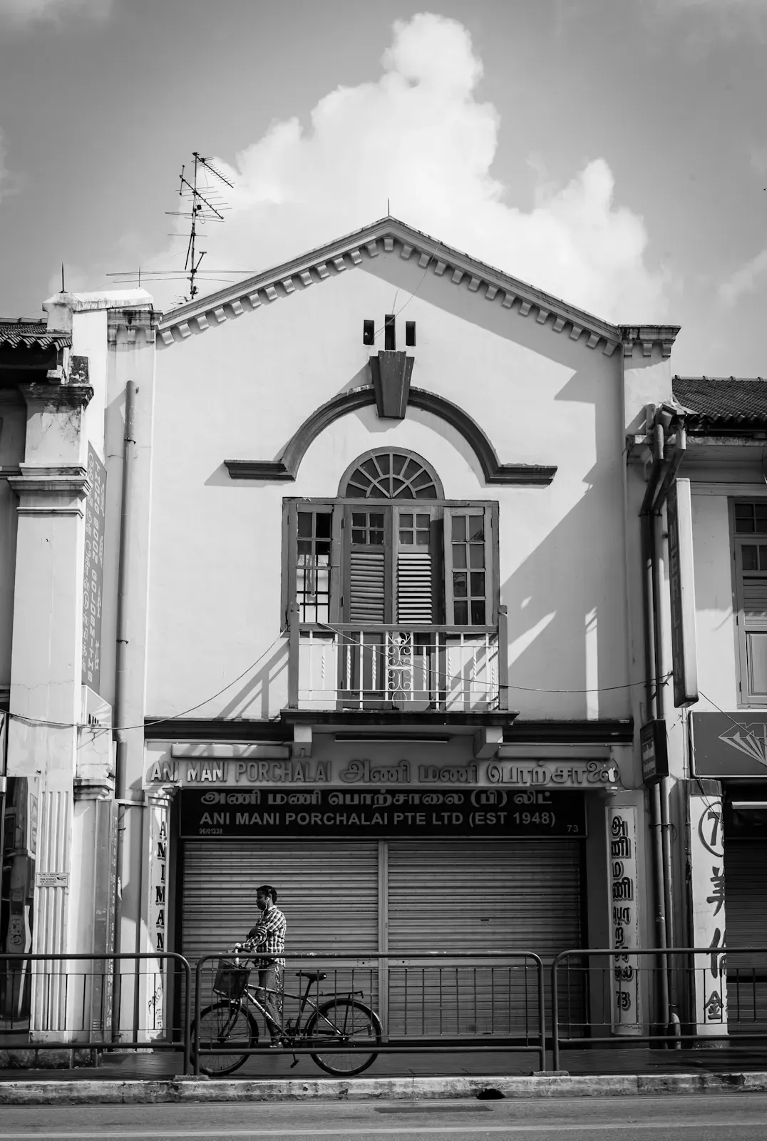 Man pushing his bicycle past a shop house in Little India