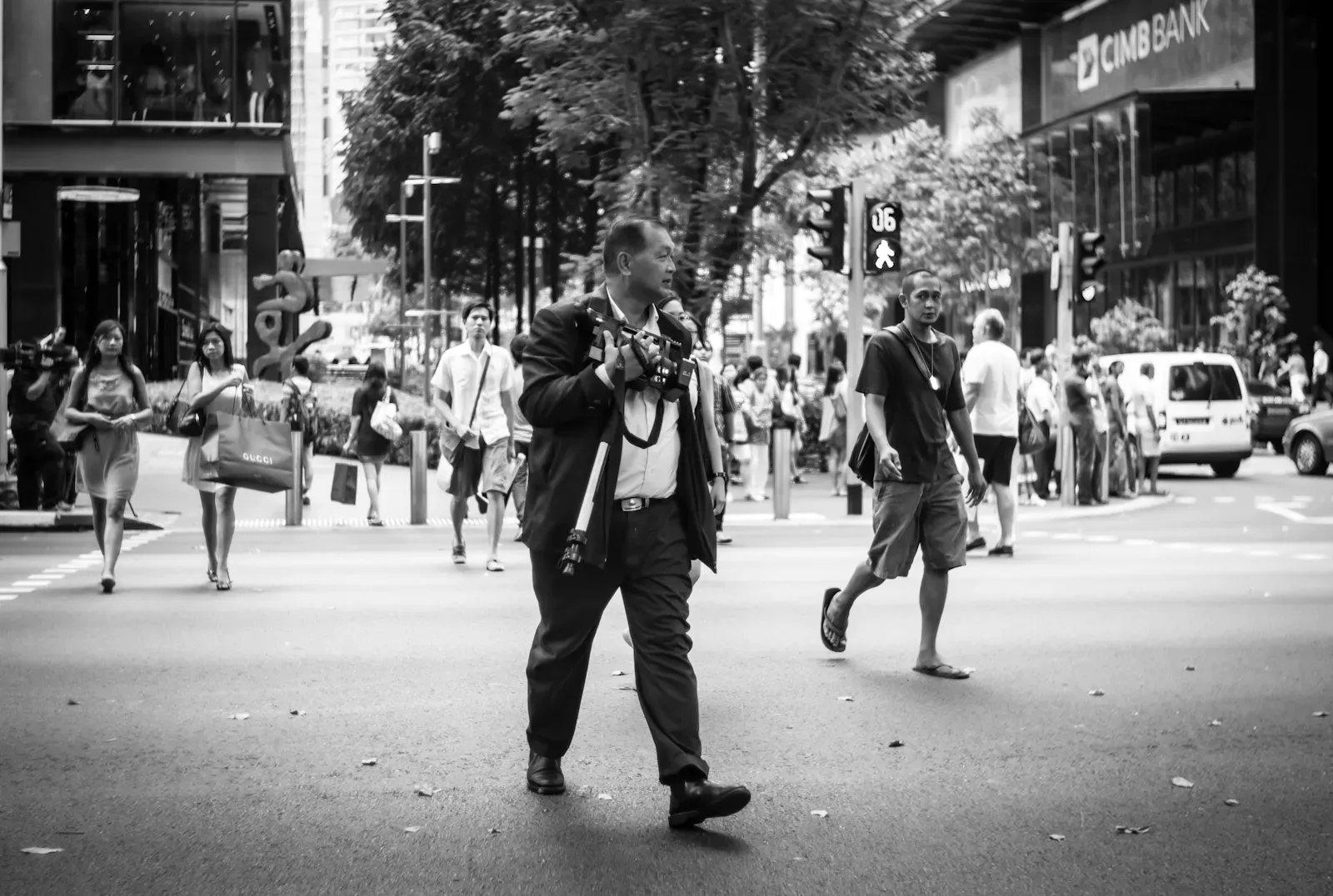 Man carrying a video camera as he walks across the road