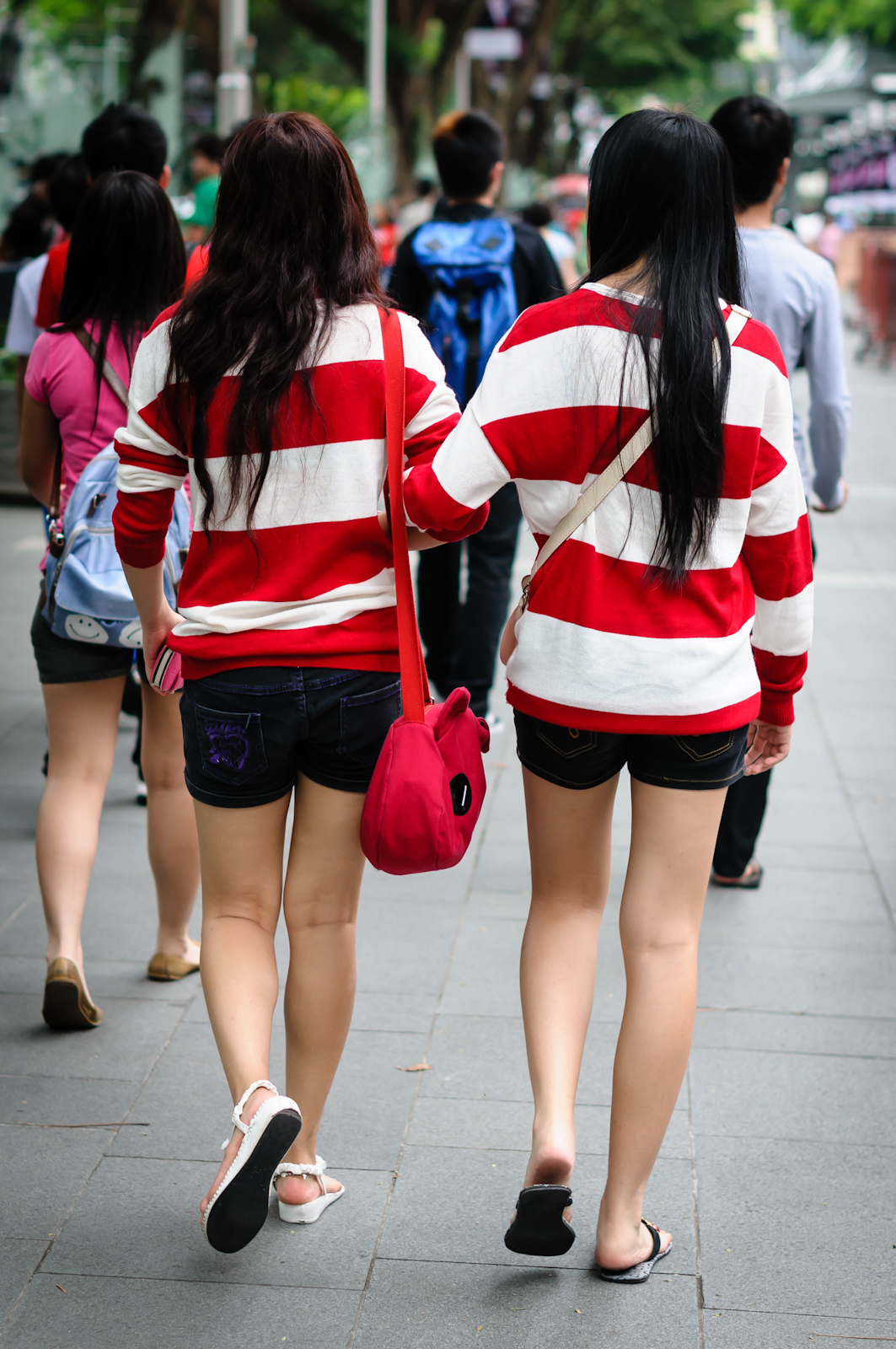 Street photography - two girls in red and white stripes holding hands
